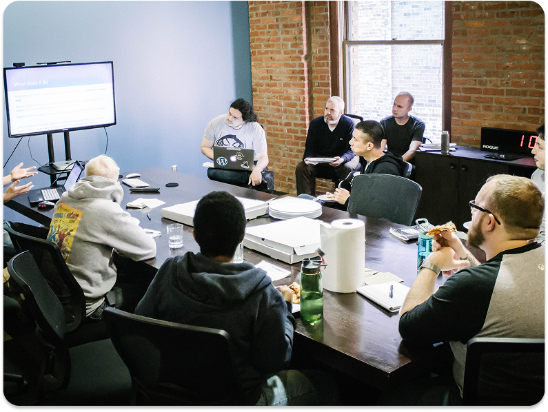 built mighty team at a conference table looking at tv monitor 